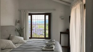 A bedroom with a large window, a bed with linens, a bedside table, and a lamp. - 3-Bed Andalusian House with Private Pool & Garden! (Pizarra)