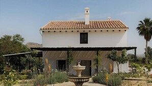 A house with a tiled roof, a central fountain, and a garden with various plants. - 3-Bed Andalusian House with Private Pool & Garden! (Pizarra)