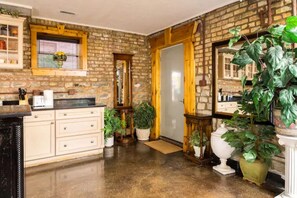 Enjoy cooking in this well-equipped kitchen with a brick wall, wooden door, and ample countertop space.