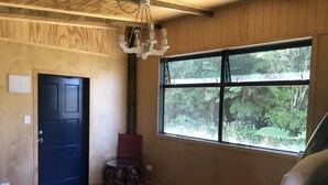 Une pièce dotée d’une grande fenêtre, d’une porte en bois, d’une table ronde en bois et d’un tapis à motifs.