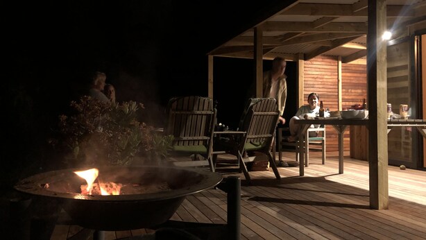 Un espace extérieur aménagé avec un foyer, une terrasse en bois et des sièges.