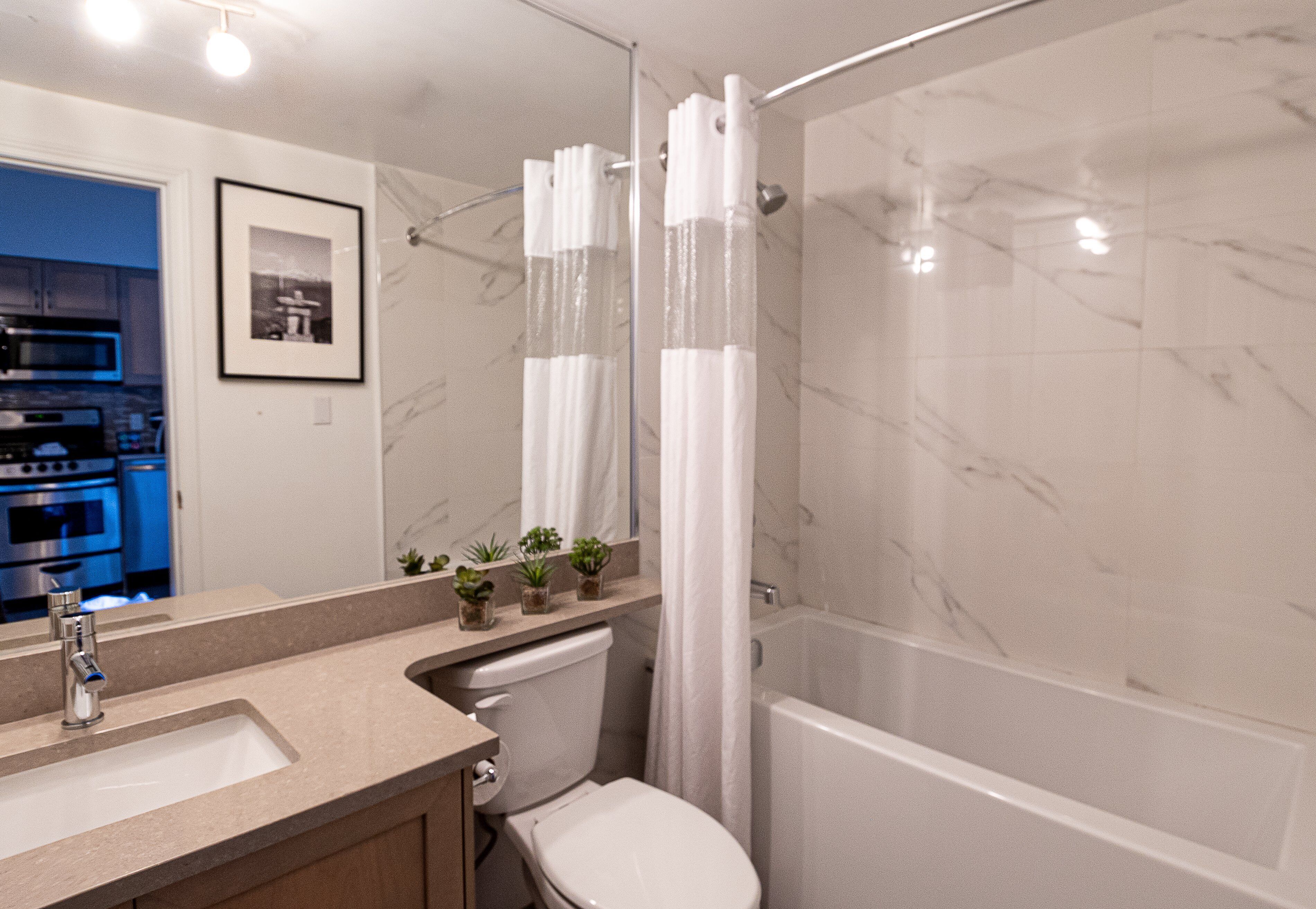 Une salle de bain avec un lavabo, des toilettes, une douche et un mur en marbre.