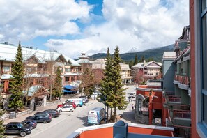 Una cittadina con edifici, una strada, auto parcheggiate e una montagna sullo sfondo.