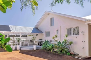 A modern house with a covered patio, outdoor seating, and potted plants.