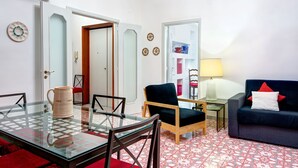 A living room with a glass table, two chairs, a sofa, a lamp, and a bookshelf. - Nice apartment for 6 guests with WIFI, A/C, TV, terrace and panoramic view (Sorrento)