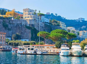 A marina with boats docked, a waterfront promenade, and buildings on a hillside. - Beautiful apartment for 4 people with WIFI, A/C and TV (Sorrento)