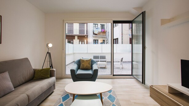 A modern living room with a sofa, a chair, a coffee table, and a TV stand. - H Gloria Suites 5 - 2 dormitorios (San Sebastián)