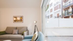 A modern living room with a sofa and armchair, a floor lamp, and a framed picture on the wall. - H Gloria Suites 5 - 2 dormitorios (San Sebastián)