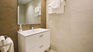 A modern bathroom with a white sink, a mirror, and two towel racks. - H Gloria Suites 5 - 2 dormitorios (San Sebastián)