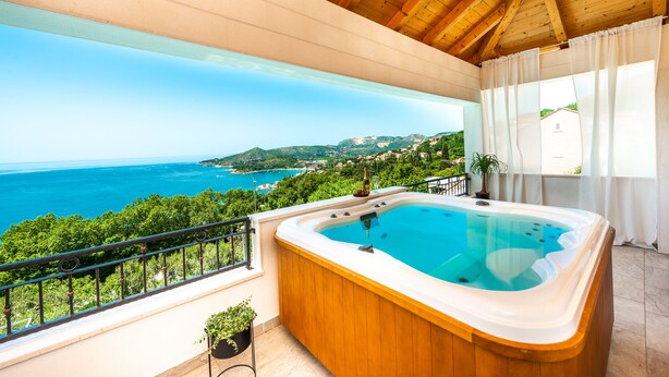 Ein Whirlpool auf einem Balkon mit Blick auf Meer und Grün.