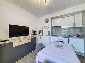 A compact kitchen with a flat-screen TV, a coffee maker, and a washing machine. - JARDINS II 1-9 Roses / Roses - INTERimmo (Rosas / Roses)