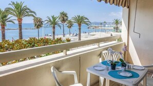Ein Balkon mit Tisch für zwei Personen, Blick auf einen Strand mit Palmen und das Meer.