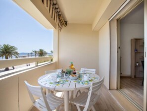 Un balcone con un tavolo rotondo e sedie, una piccola pianta e una bottiglia d'olio.