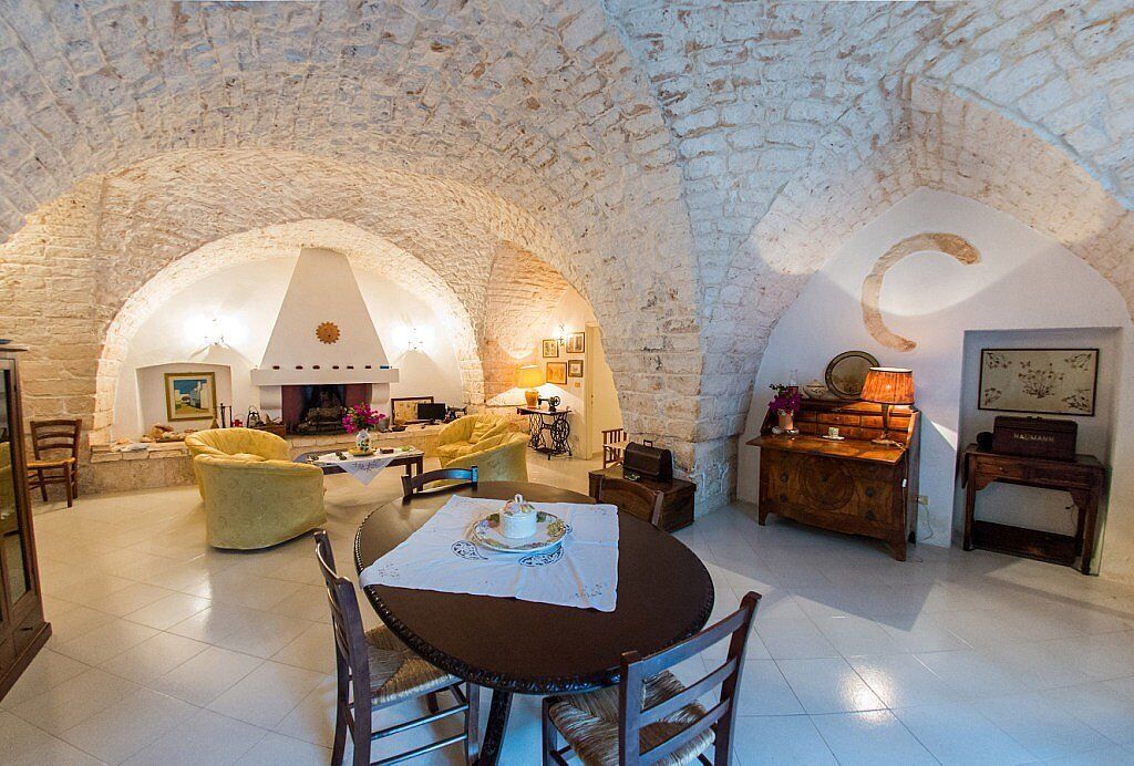 Ein gemütliches Wohnzimmer mit einer Steinkuppel, einem runden Esstisch mit Stühlen, einer Couch und einem Kamin.