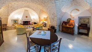 A cozy living room with a stone vaulted ceiling, a round dining table with chairs, a sofa, and a fireplace.