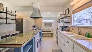 Een moderne keuken met een centraal eiland, geïntegreerde apparatuur en een groot raam met uitzicht op buiten.