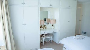 A bedroom with a large wardrobe, a desk with a mirror, two bedside tables, and a bed. - Beautiful 3 Bedroom Home in Staines Private Parking, Garden, Near Heathrow (Staines-upon-Thames)