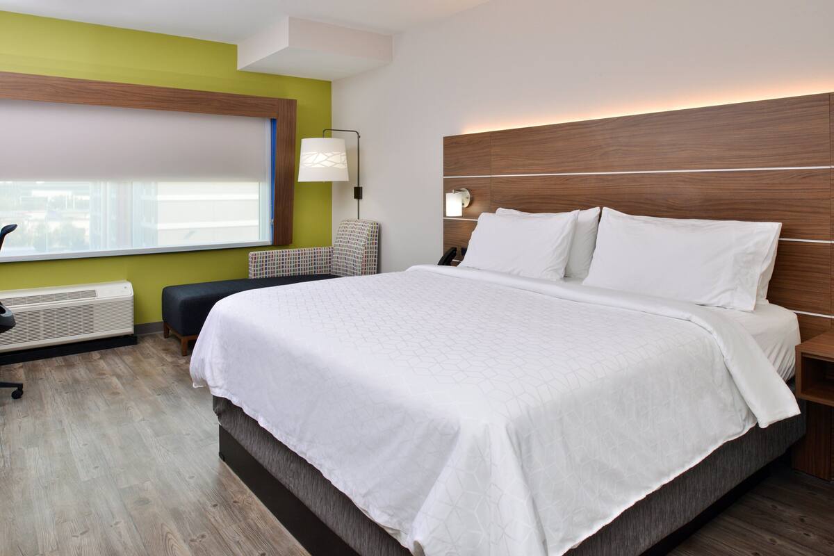 Una habitación de hotel moderna con una cama grande, un escritorio y una silla.