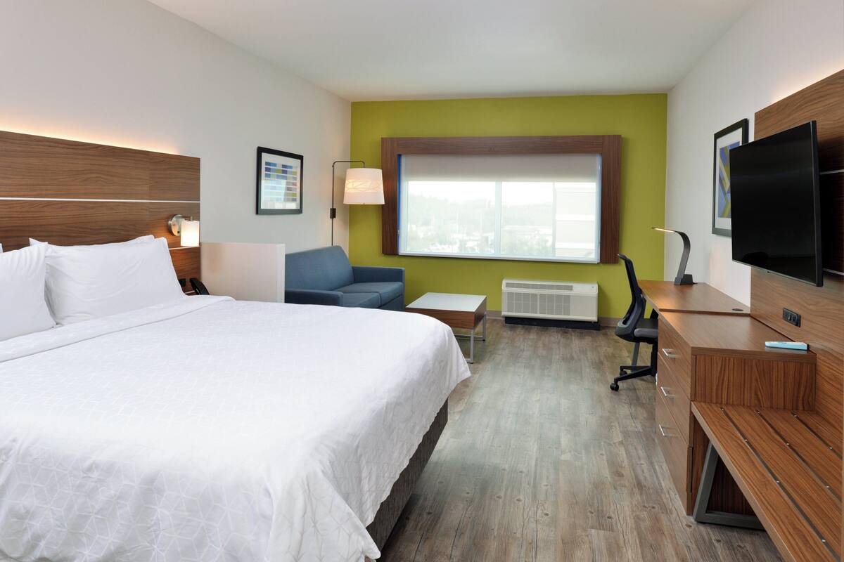 Habitación de hotel con una cama grande, un escritorio, una silla, un televisor y una ventana con vistas.
