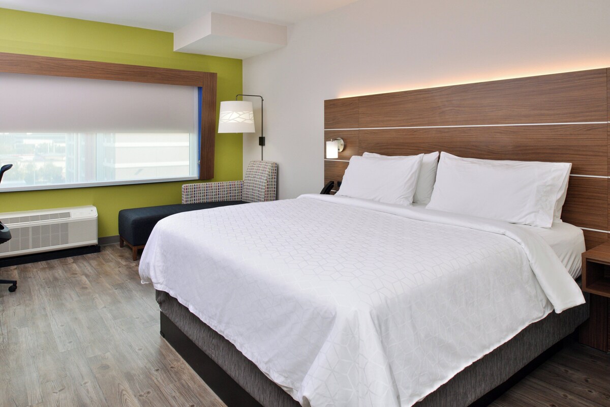 Una habitación de hotel moderna con una cama grande, un escritorio y una silla.