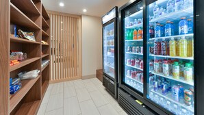Una habitación de hotel moderna con estantes de madera llenos de aperitivos y un minibar.