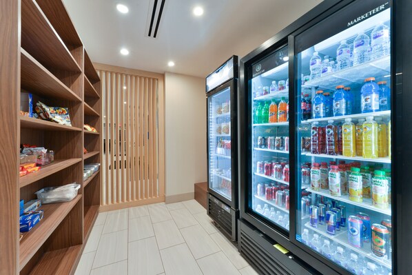 Een moderne hotelkamer met houten planken vol snacks en een minibar.