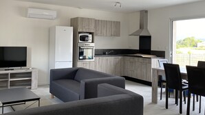 Una sala de estar moderna con un sofá gris, un televisor de pantalla plana y un comedor con mesa y sillas.