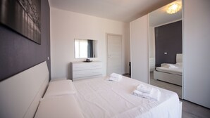 Une chambre à coucher moderne avec un grand lit, une commode, un miroir et un dressing.