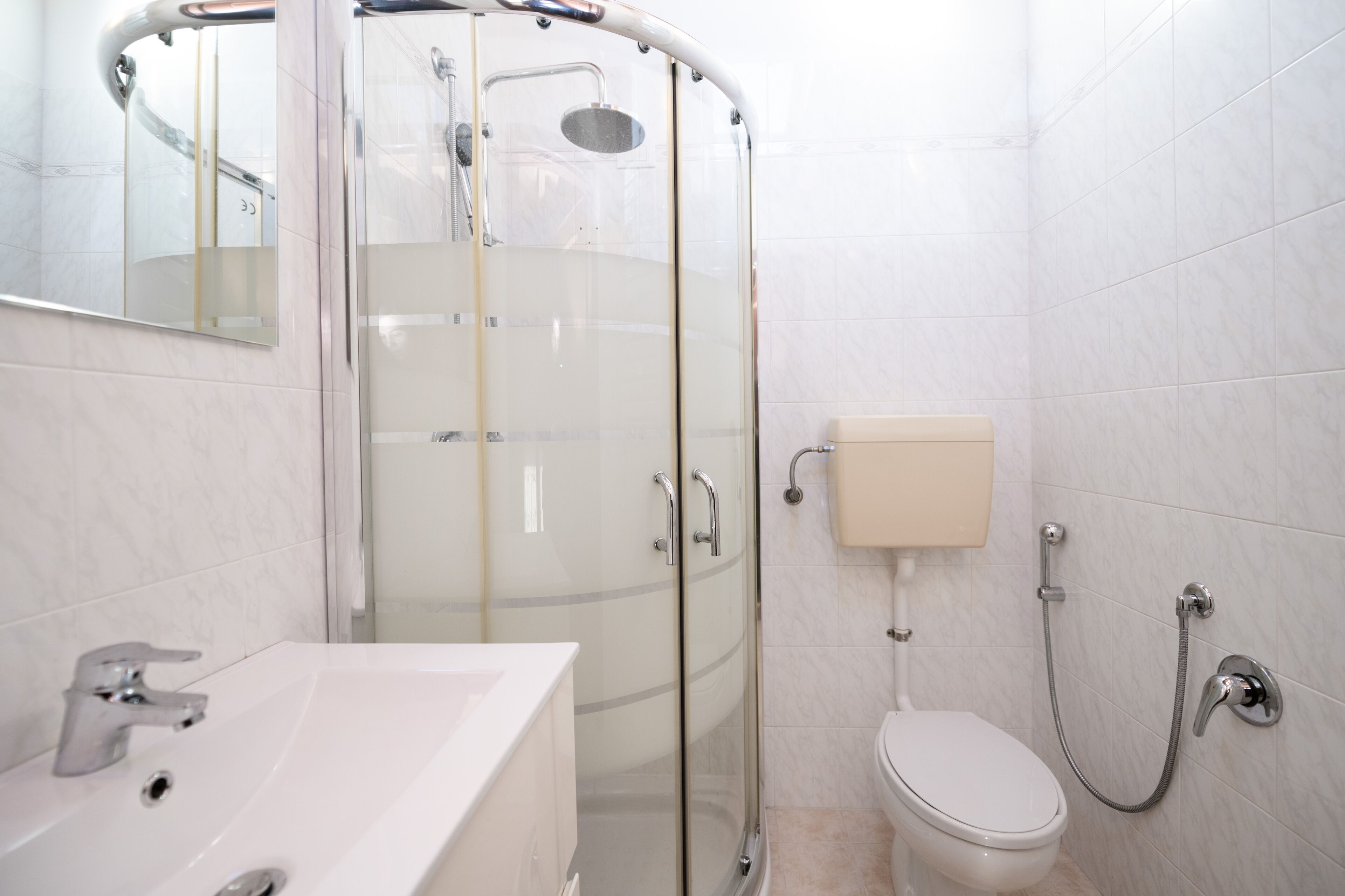 A modern bathroom with a glass-enclosed shower, a white sink, and a toilet.