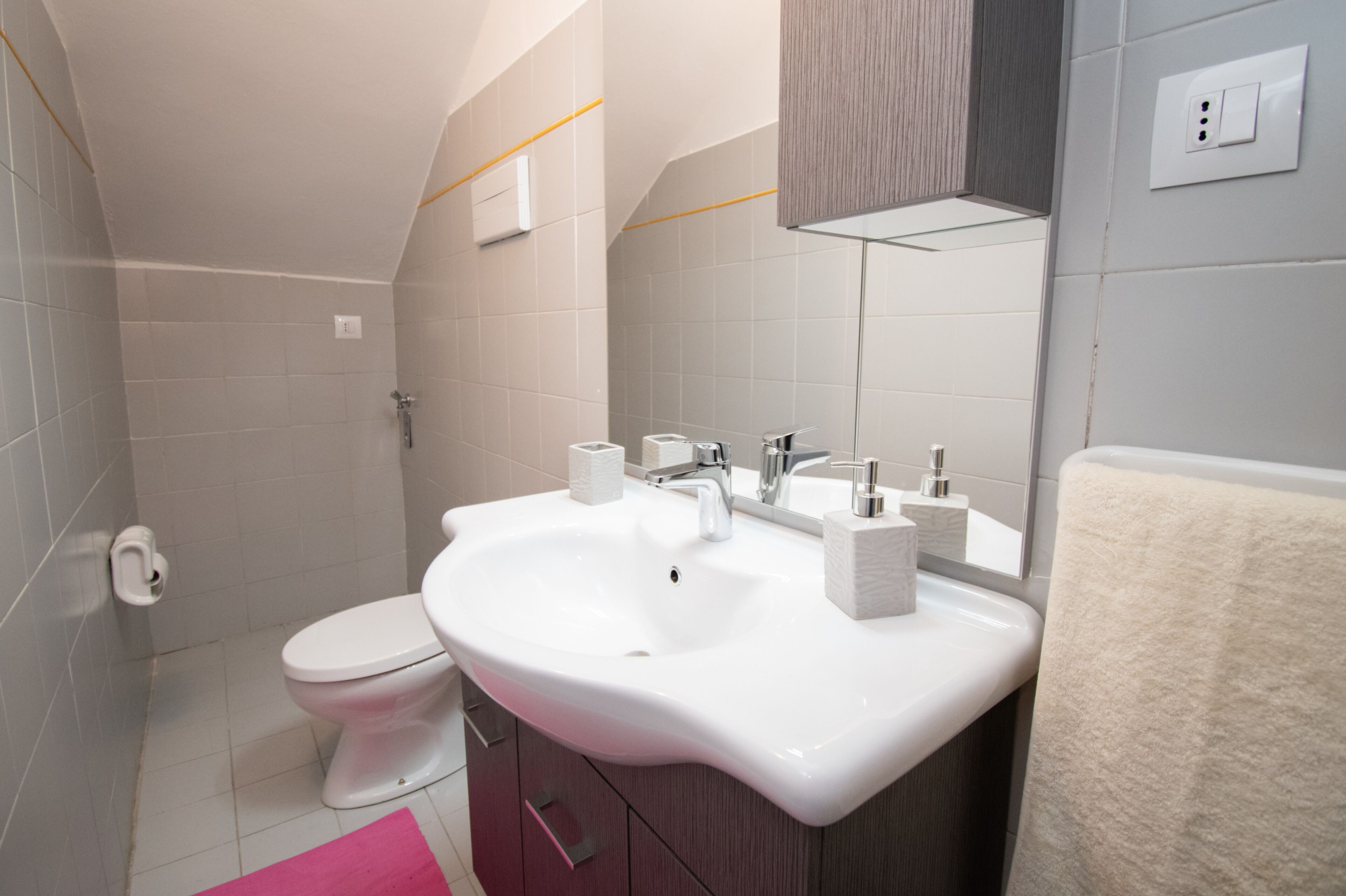 Un baño moderno con lavamanos blanco, inodoro y espejo.