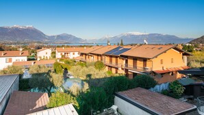 Un quartier résidentiel où les maisons se distinguent par leurs toits recouverts de tuiles rouges, leurs panneaux solaires et leur vue sur les montagnes et un lac.
