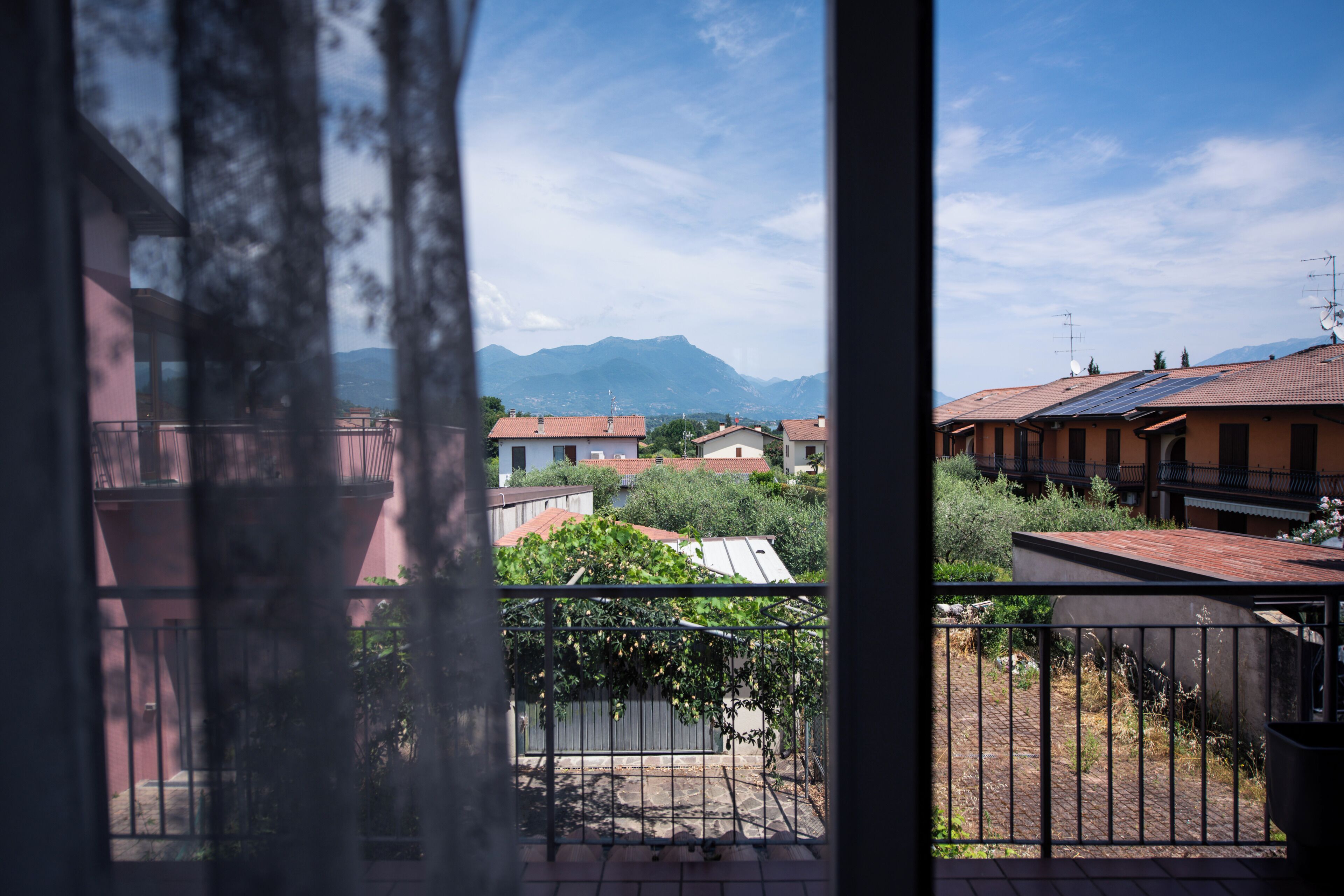 A balcony with a view of a residential area, including houses and mountains.