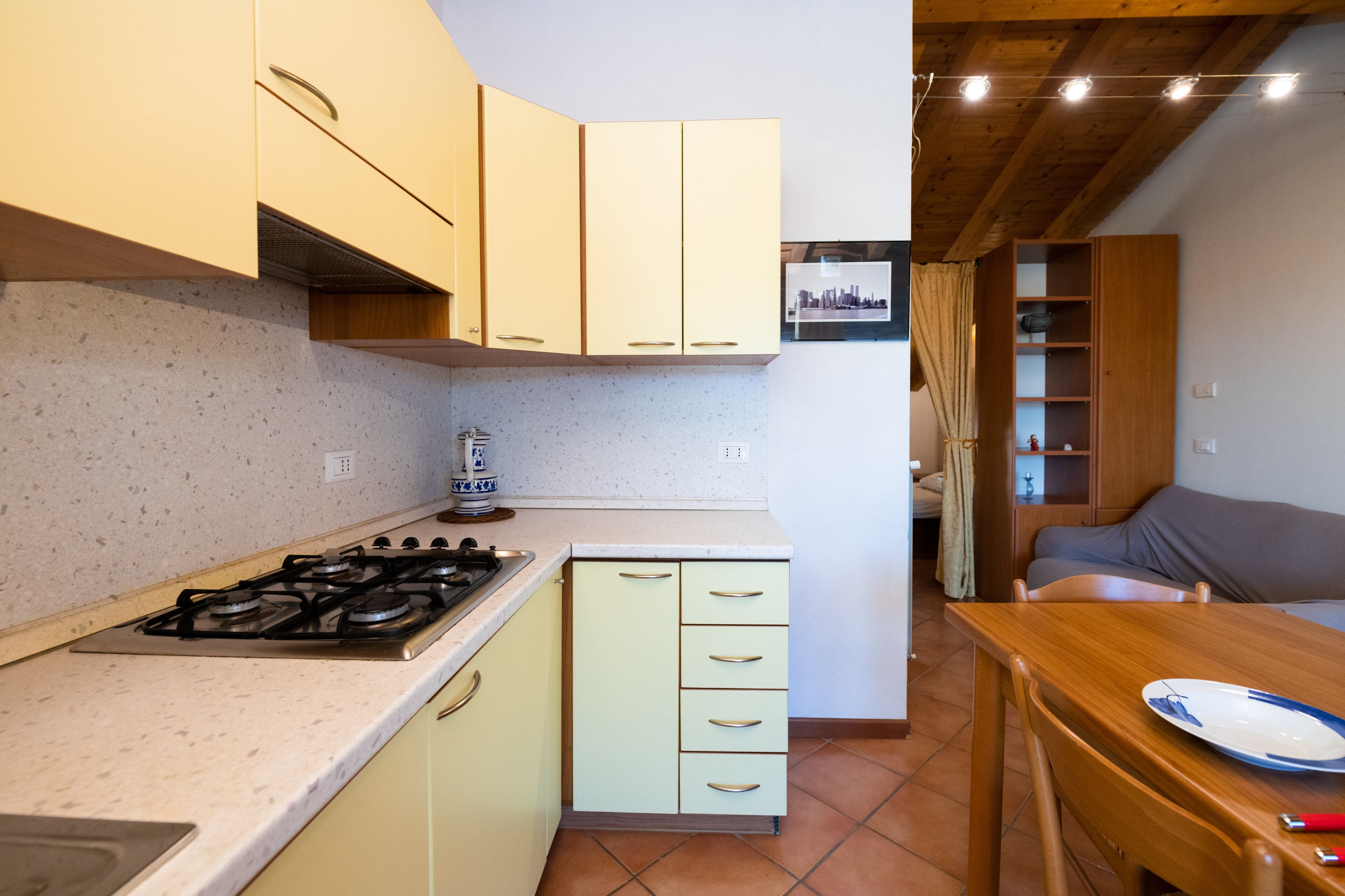 A compact kitchen with a gas stove, light-colored cabinets, and a dining area with a table and chairs.
