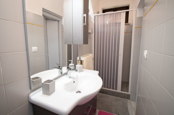Un bagno moderno con lavandino bianco, specchio e porta asciugamani.
