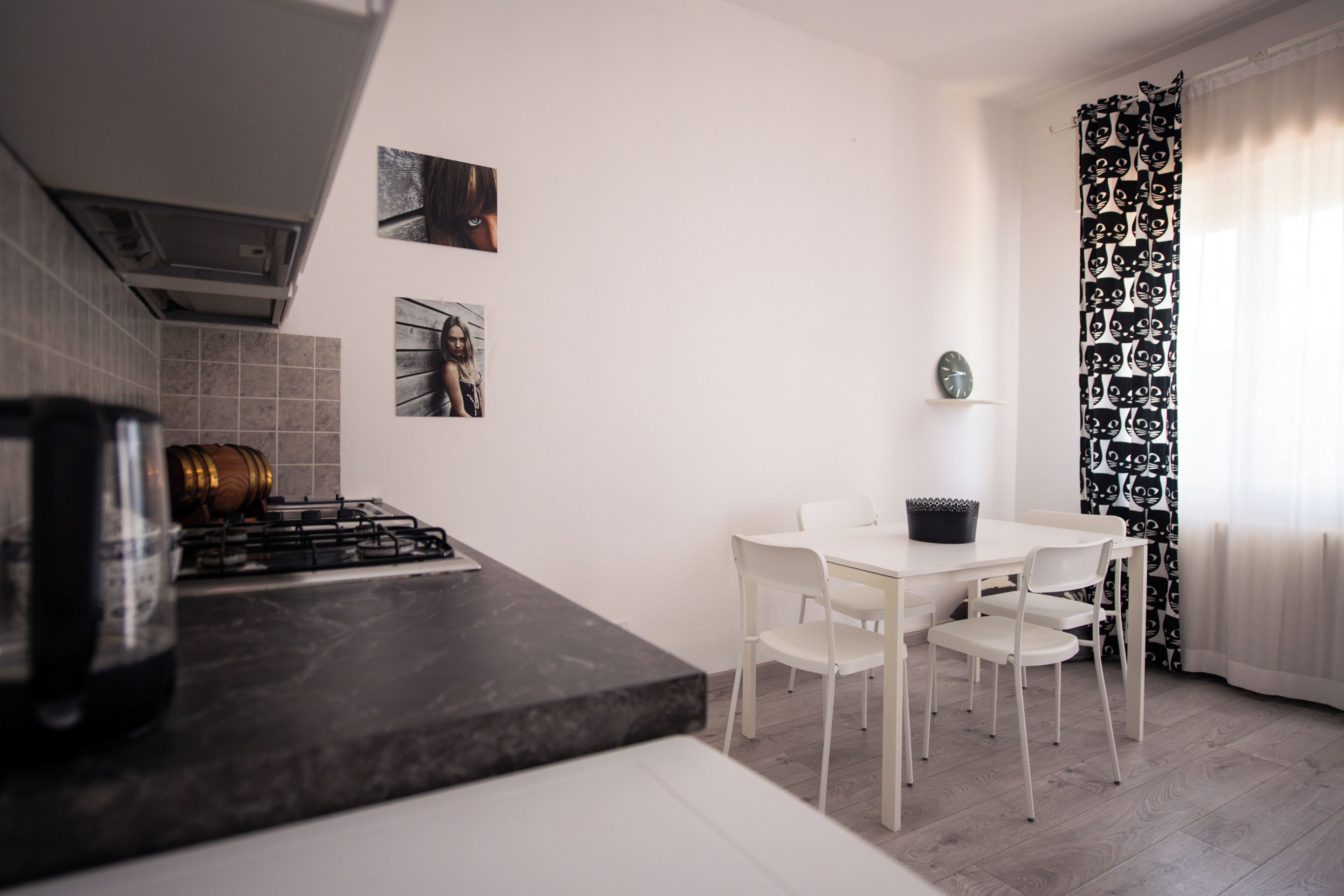 Una cocina moderna con armarios blancos, cocina a gas y comedor con sillas y mesa blancos.