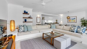 A modern living room with a sofa, coffee table, and shelves. - Belle Escapes 42 Alamanda Palm Cove (Palm Cove)