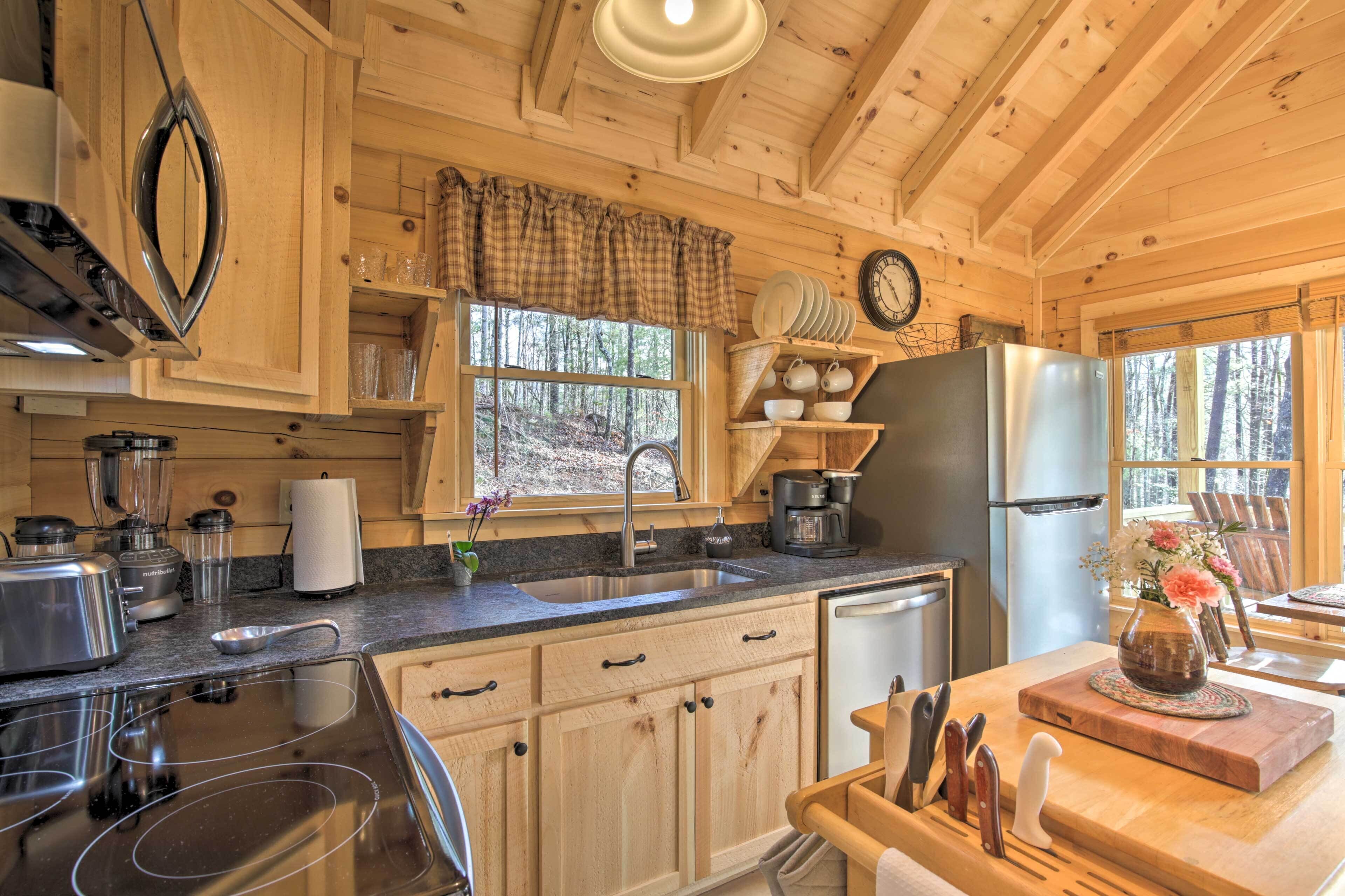 A wooden cabin kitchen with a sink, stove, refrigerator, and wooden cabinets.