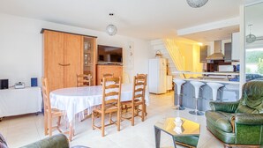 Ein modernes Wohnzimmer mit Essbereich, einer Küche und einer Treppe, die in eine obere Etage führt.