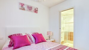 Ein Schlafzimmer mit einem Bett, Kissen, einer Nachttischlampe und einem Wandbild.