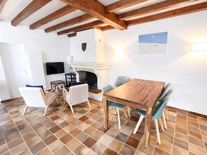 A dining area with a wooden table and chairs, a fireplace, and a television mounted on the wall.