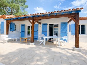 A covered outdoor seating area with a table and chairs, a bench, and a pergola structure.