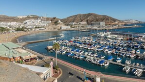 Un port de plaisance avec des bateaux amarrés, une plage et des bâtiments en arrière-plan.