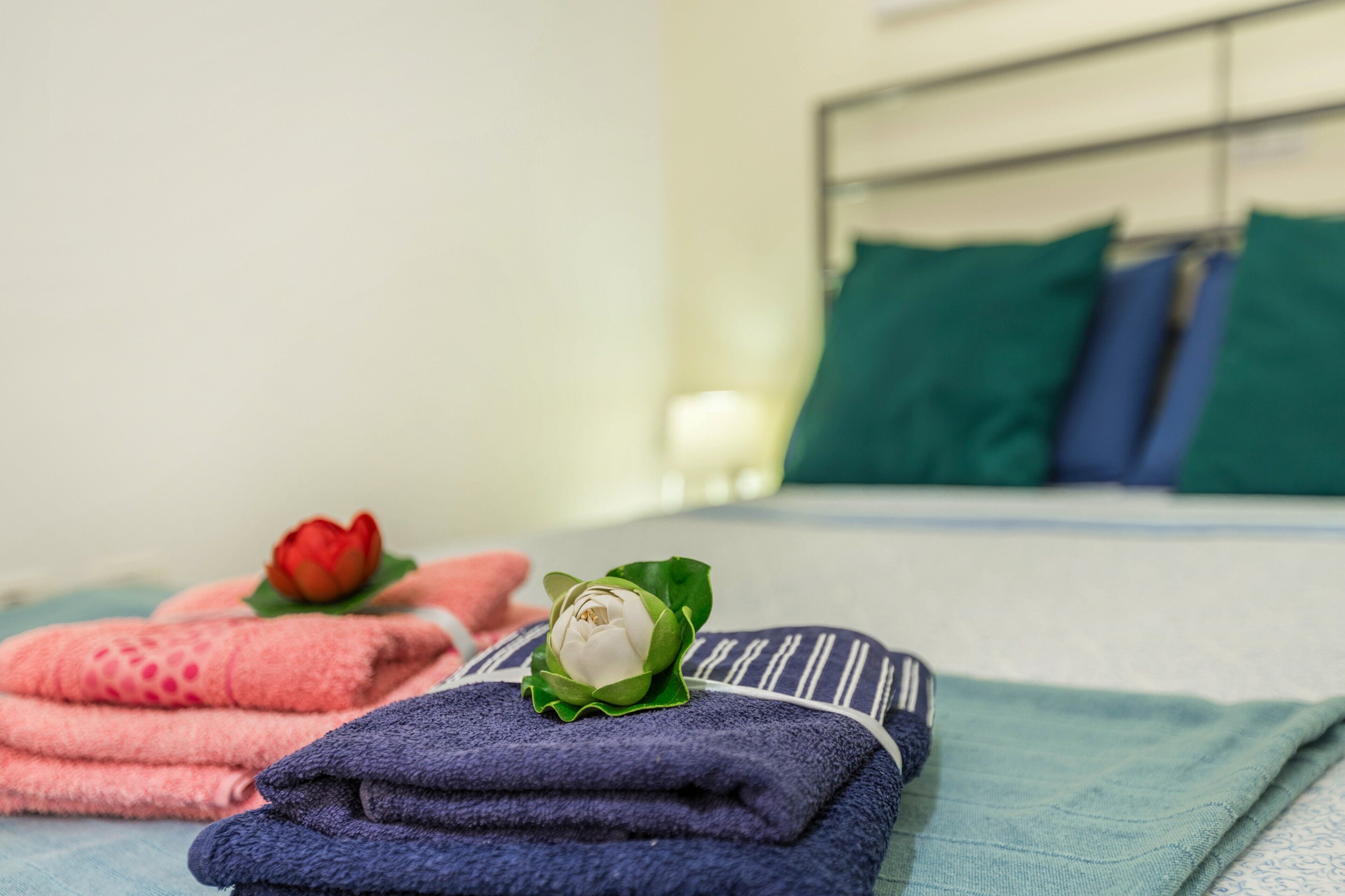 Ein ordentlich bezogenes Bett mit gefalteten Handtüchern und einer Zierblume.