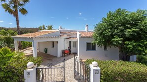 Una casa con techo de tejas, entrada protegida por una reja y zona de patio.