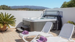 Un jacuzzi con dos sillones reclinables, una planta en maceta y vistas a las colinas.