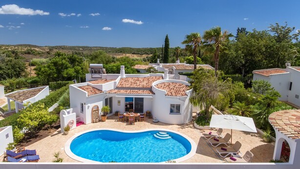 Una villa con piscina, mobiliario de exterior y vistas del paisaje circundante.