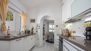 Una cocina moderna con armarios blancos, electrodomésticos de acero inoxidable y vistas a un comedor a través de un arco.