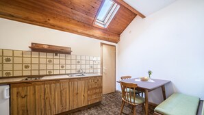 Una cocina con armarios de madera, salpicadero de azulejos, tragaluz y una zona de comedor con banco.