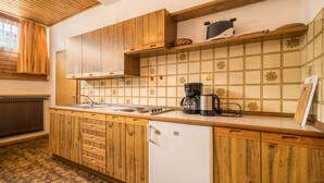 Een keuken met houten kastjes, een witte koelkast, een koffiezetapparaat en een betegelde achterwand.