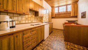 Una cucina con mobili in legno, un frigorifero bianco, una macchina per il caffè e una finestra con tende.